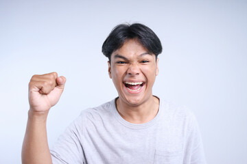 Excited Young Asian Guy Clenching Fist Showing Victory Gesture Isolated On White Background
