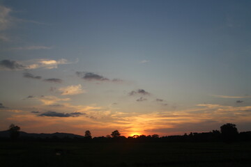 Natural Sunset Sunrise Over Field Or Meadow. Bright Dramatic Sky And Dark Ground. Countryside Landscape Under Scenic Colorful Sky At Sunset Dawn Sunrise. Sun Over Skyline, Horizon. Warm Colours.