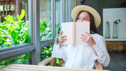 Portrait image of a beautiful young woman with hat holding and reading book