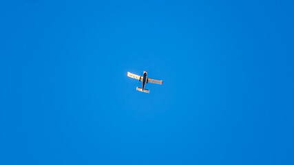Small ultralight airplane with overhead wing and single propeller flying in sunset sky.