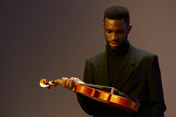Elegant man in suit holding a violin against a dark background for music and arts concept