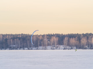 Kite surfer ride on snowboard. Snowkiting in the snow on frozen lake.