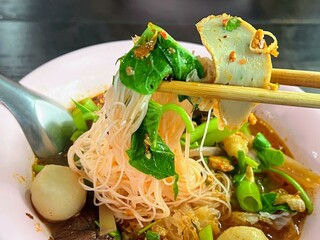 a photography of a bowl of food with chopsticks and noodles.