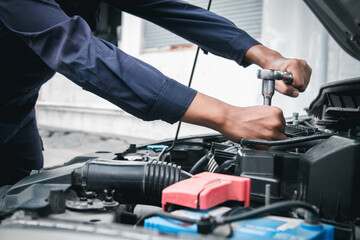Mechanic using wrench while working on car engine outside the service center , Repair and service.