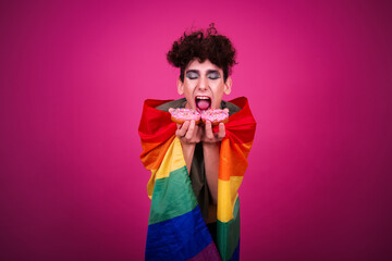A funny guy dressed as a drag queen and eating pink donuts. Pink background.