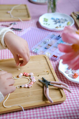 Set of multi-colored ceramic and plastic beads for needlework, child and mother are making jewelry...