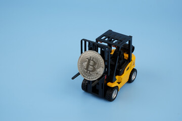 Forklift truck carrying bitcoin on blue background, space for text.
