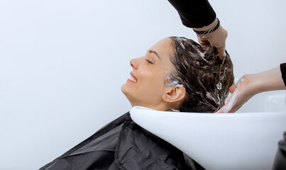 Woman professional hairdresser washing hair in a beauty salon, doing hair styling to client in...
