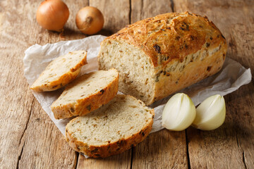 Yeast onion bread loaf with a crispy crust close-up on parchment on a wooden table. Horizontal