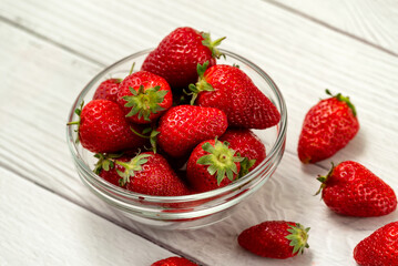 Bowl with strawberries on a white wooden background