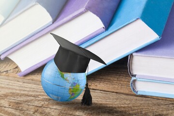 Graduation cap on Earth globe and set of books