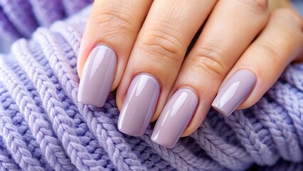 A close-up photograph displays a hand with well-manicured, short fingernails painted in a matte, muted purple shade, held against a softly blurred, neutral-toned background.