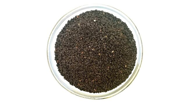 Black cumin seeds or black caraway seeds in a glass bowl isolated rotating on white background, a glass bowl full of Black cumin seeds or black caraway seeds top view, close up, herbs and spices