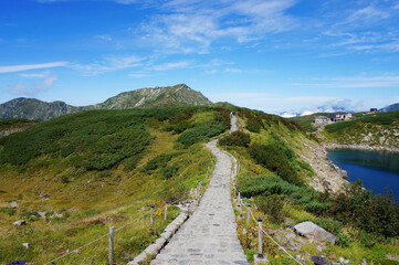 よく晴れた青空と立山の風景と石畳の遊歩道