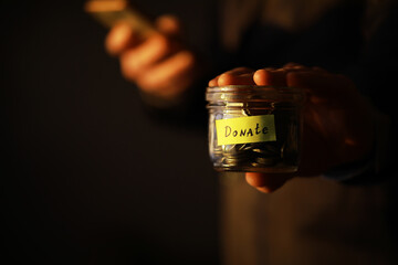 Businessman hand putting money (coin) in the glass jar, vintage tone effect