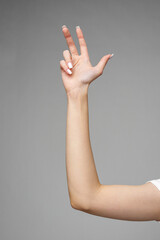 Female hand gesturing sign against gray background