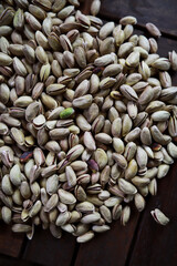 Pistachio nut in sack bag with mint green leaf on wooden table background.