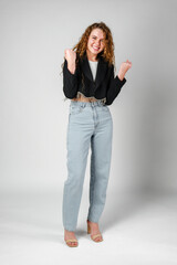 Excited Young Woman Celebrates Success With Raised Fists Against a Gray Background