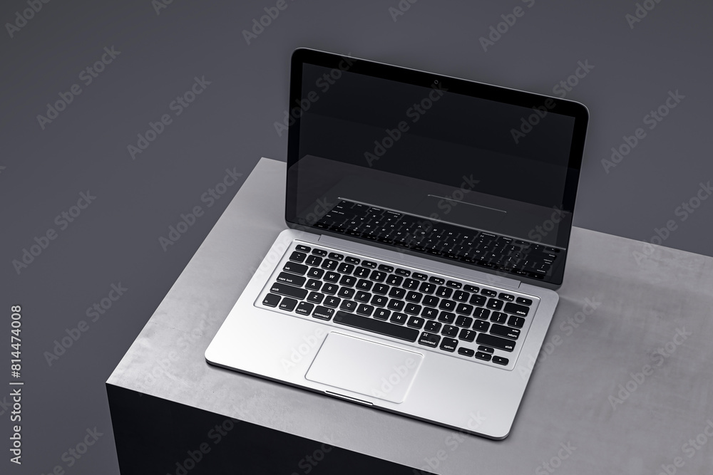 Poster stylish laptop on a minimalistic gray podium, featuring a dark screen for sophisticated tech present