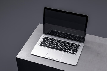 Stylish laptop on a minimalistic gray podium, featuring a dark screen for sophisticated tech presentations. 3D Render