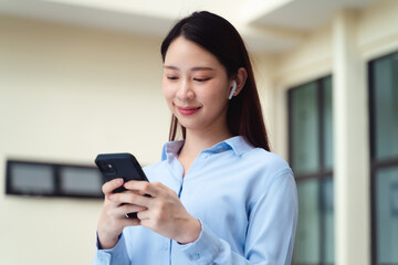 Obraz premium A business woman is using the smart phone while standing outside