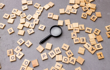 Square letter tiles with magnifying glass against blue background. Search for words and information...