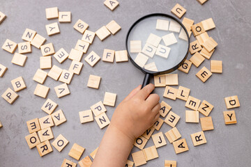 Square letter tiles with magnifying glass against blue background. Search for words and information...