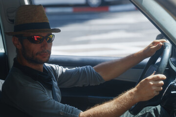 Man in straw hat and sunglasses driving a car during daytime