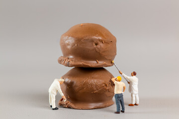 Miniature worker team painted chocolate ball  on a gray background, world chocolate day concept