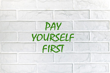 Business, finance, economic concepts. PAY YOURSELF FIRST writing on the wall is made of white decorative bricks