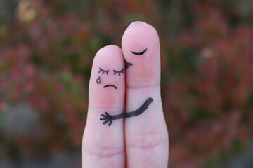 Fingers art of displeased couple. Woman cries, man reassures her. He kisses and hugs her.