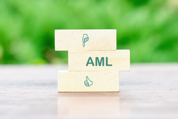 AML Anti Money Laundering Finance Business Concept. on wooden blocks in front of a green background of green leaves out of focus