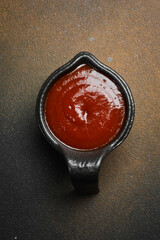 Ketchup sauce or tomato paste in a black sauce pan. Sauces for meat.