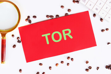 TOR Terms Of Reference on red paper on a white background with coffee beans and a magnifying glass
