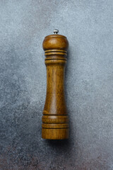 Top view close up wooden pepper mill on concrete gray background.