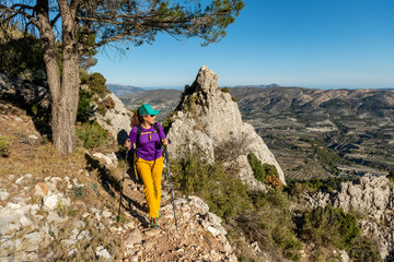 Obraz premium A woman hiking in the mountains, Serrella peak, Quatretondeta, Alicante, Spain - stock photo
