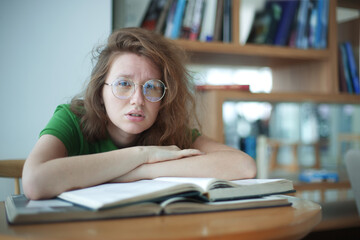 Portrait of serious concentrated, young woman in glasses college or university student is study...