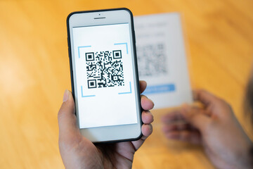 Close up of customer hand making payment through smart phone and scan code.