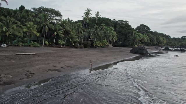 Blonde woman walking along a wild tropical beach alone