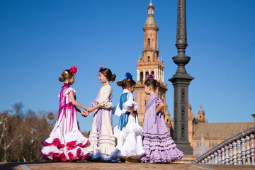 Four little girls dancing flamenco dressed in typical flamenco dress talk to each other in a famous...