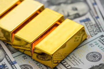 Lot of gold bars overlay us dollar banknotes.  Financial treasure background