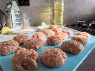 Raw meatballs from minced beef and pork meat on a blue cutting board