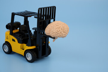 Forklift truck carrying human brain on blue background. Copy space for text.