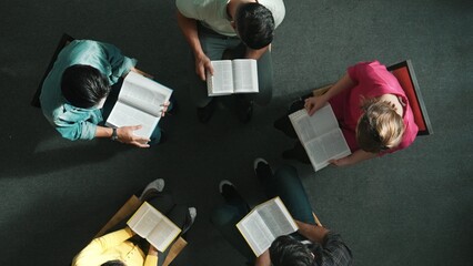 Top down view of prayer reading at bible book and sitting in circle with bible book on laps. Aerial...