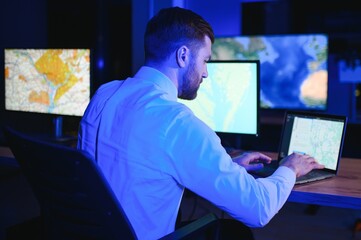 Male Data Scientist Works on Personal Computer Control and Monitoring Room. Map Surveillance of...