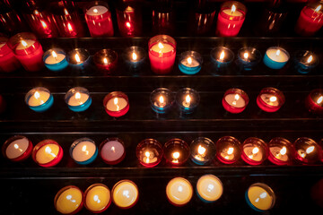 Velas acesas a arder nos candelabros ou castiçais no interior escuro de uma Igreja