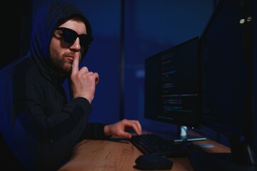 hacker sitting at desk in dark atmosphere. A computer programmer or hacker. Anonymous computer...