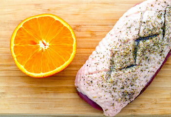 duck fillet with seasonings and orange on a wooden cutting board