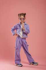 Colorful sweet candy in hand. Cute little girl is against pink background