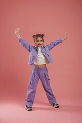 Naklejka premium Dancing, having fun. Cute little girl is against pink background